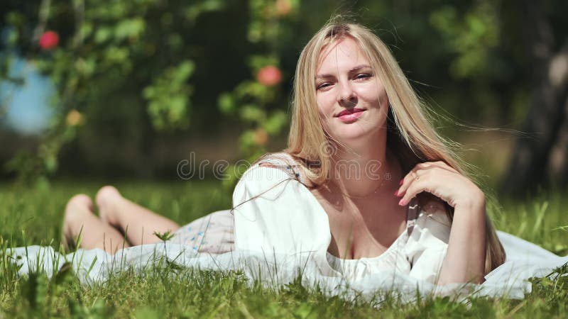 Ein blondes Mädchen liegt in einer Räumung in einem Apfelgarten.