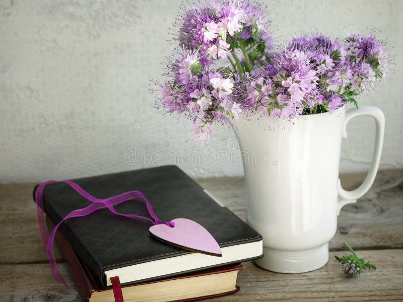 Ein Blumenstrauß von purpurroten Blumen, Bücher auf einem alten Holztisch lizenzfreies stockfoto Ein Blumenstrauß von purpurroten Blumen, Bücher auf einem alten Holztisch lizenzfreies stockfoto