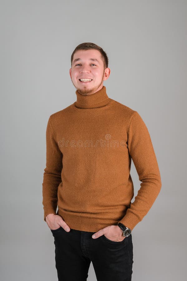 Ein bärtiger Mann lacht mit seinen Händen in den Taschen und steht auf grauem Hintergrund lizenzfreie stockbilder