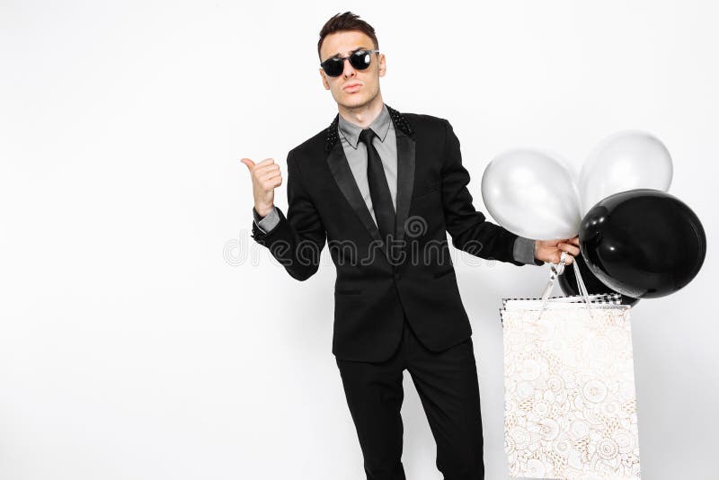 Ein eleganter Mann in einem schwarzen Anzug, mit Taschen in seinen Händen und Ball stockfoto Ein eleganter Mann in einem schwarzen Anzug, mit Taschen in seinen Händen und Ball stockfoto