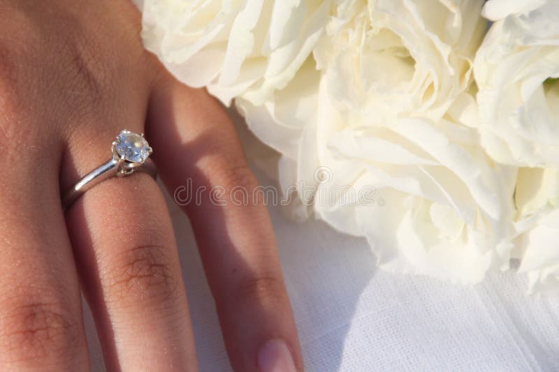 Ein eleganter Verpflichtungsdiamantring auf einer Frau ` s Hand und ein Blumenstrauß von weißen Lisianthus-Blumen stockbilder Ein eleganter Verpflichtungsdiamantring auf einer Frau ` s Hand und ein Blumenstrauß von weißen Lisianthus-Blumen stockbilder