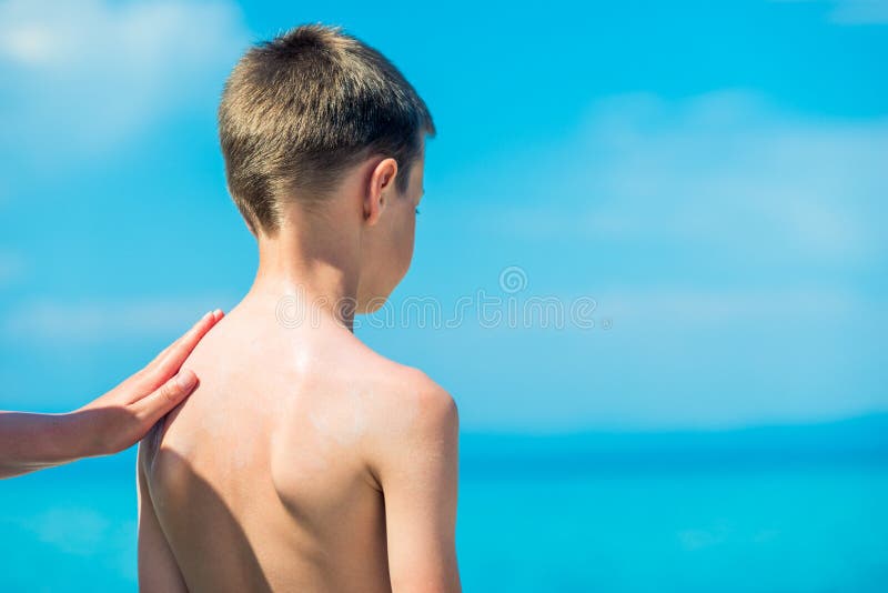 Ein Elternteil ein Kind mit Sonnenschutzmittel verschmiert. Sonnenschutz. Sonnenbrand verhindern stockbild