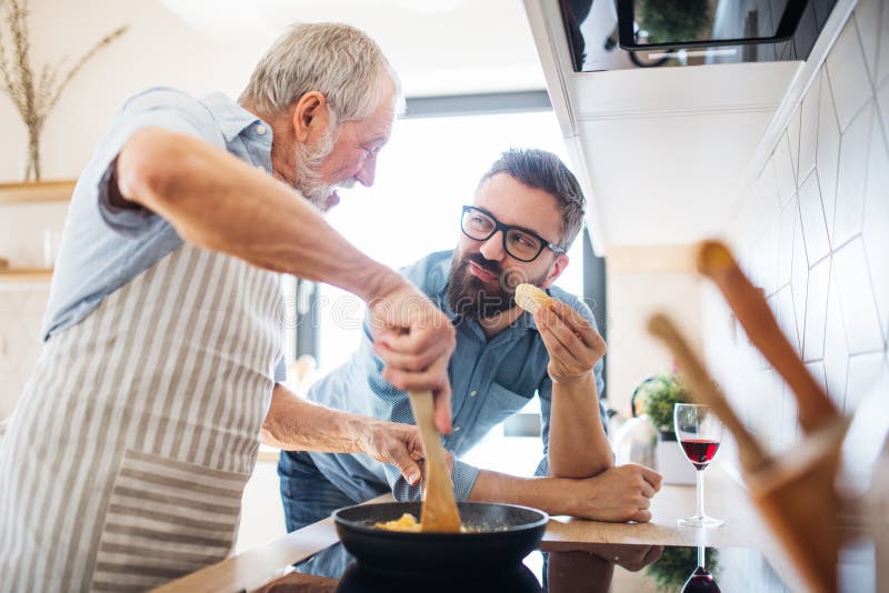 Ein erwachsener Hippie-Sohn und ein ?lterer Vater zuhause zu Hause, kochend stockbilder Ein erwachsener Hippie-Sohn und ein ?lterer Vater zuhause zu Hause, kochend stockbilder