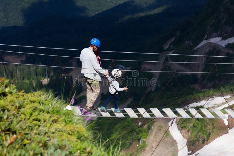 Ein erwachsener Mann und ein kleiner Junge in kletternden Gang auf einer extremen Brücke gehen stockfotos Ein erwachsener Mann und ein kleiner Junge in kletternden Gang auf einer extremen Brücke gehen stockfotos