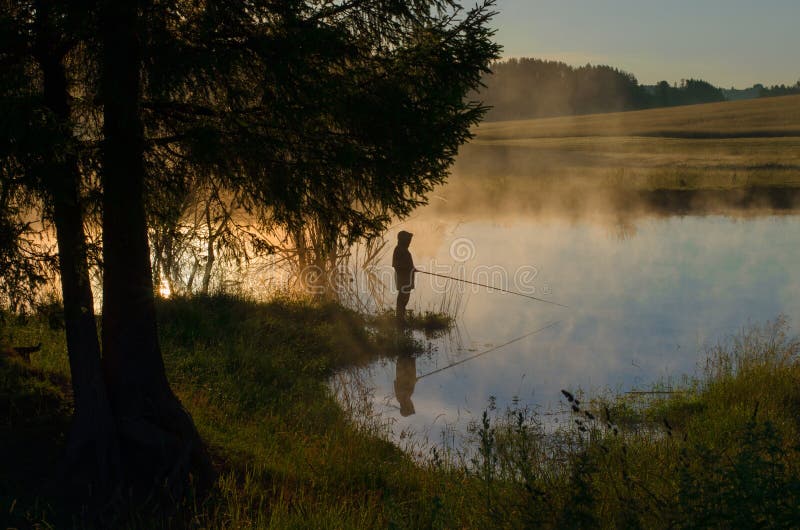 Ein Fischer auf einem bewaldeten See im Nebel lizenzfreie stockfotografie Ein Fischer auf einem bewaldeten See im Nebel lizenzfreie stockfotografie