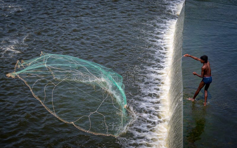 Ein Fischer an Kr-Verdammung nahe Krishnagiri, das sein Formnetz wirft