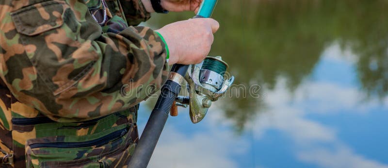 Ein Fischer mit einer Angelrute Nahaufnahme einer Hand, die eine spinnende Stange hält und eine Spule verdreht Bunte Ansicht, uns stockbild Ein Fischer mit einer Angelrute Nahaufnahme einer Hand, die eine spinnende Stange hält und eine Spule verdreht Bunte Ansicht, uns stockbild