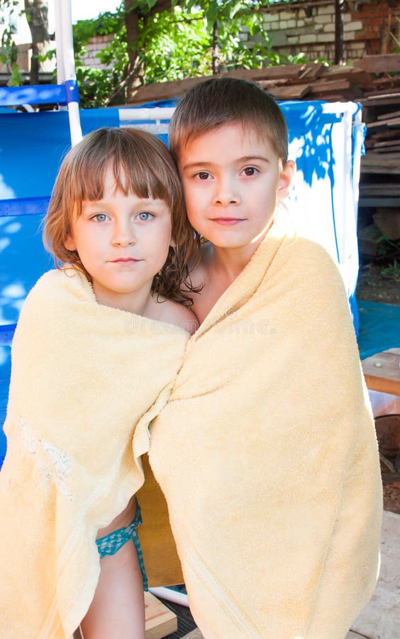 Ein fröhliches Mädchen und ein Junge werden in einem Tuch eingewickelt lizenzfreies stockfoto Ein fröhliches Mädchen und ein Junge werden in einem Tuch eingewickelt lizenzfreies stockfoto
