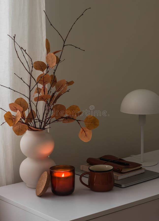 Ein gemütliches Herbstleben in einer Vase mit Herbstbukett, einer beleuchteten Kerze, Kaffeemaschine und einem Laptop auf einem we stockbilder