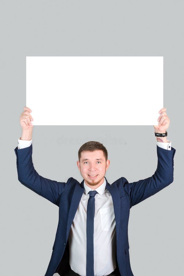 Ein Geschäftsmann in formeller Kleidung hält ein rechteckiges weißes Plakat-Mockup lizenzfreies stockbild