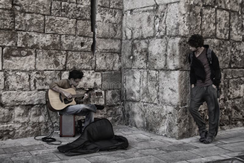 Ein Gitarrist spielt in der Straße, während Leute hören stockfoto Ein Gitarrist spielt in der Straße, während Leute hören stockfoto