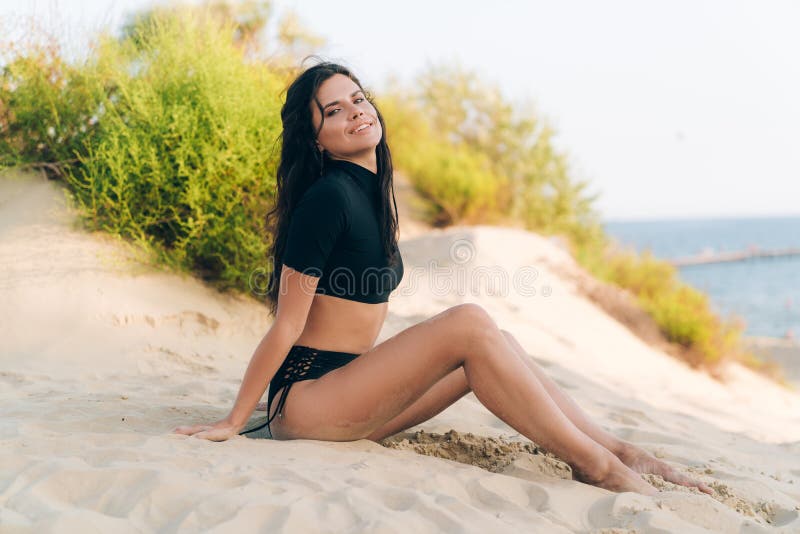 Ein glücklicher junger Student, kam stillzustehen und nahm auf einem weißen sandigen Strand in ihrem modernen Badeanzug ein Sonne lizenzfreies stockfoto