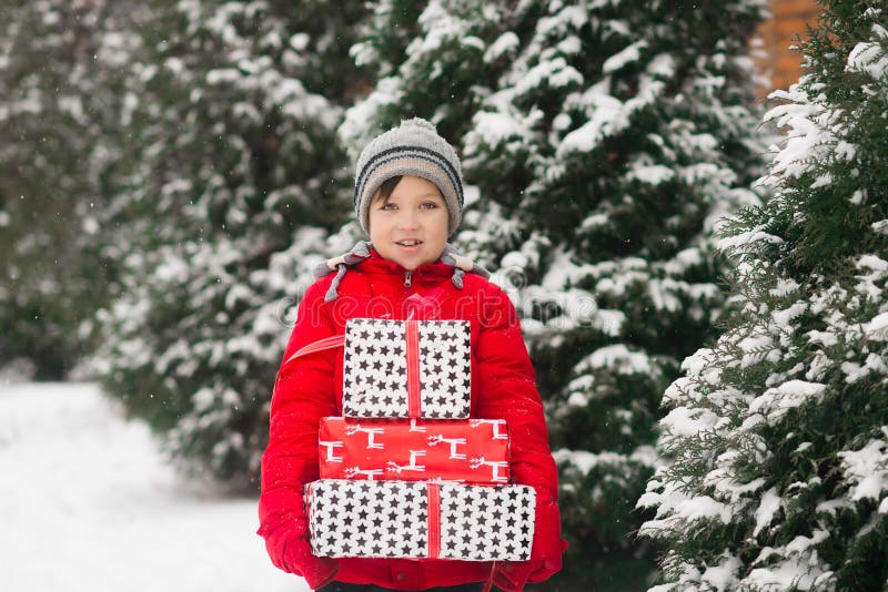 Ein glücklicher Kinderjunge hält einige Weihnachtsgeschenke in seinen Händen lizenzfreie stockbilder Ein glücklicher Kinderjunge hält einige Weihnachtsgeschenke in seinen Händen lizenzfreie stockbilder
