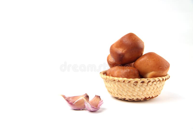 Ein Haufen Brötchen im Weidenkorb und Knoblauchzehen isoliert auf weißem Hintergrund stockbild
