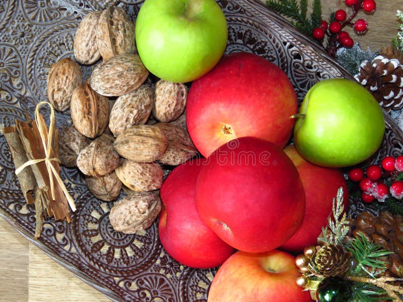 Ein Haufen Früchtepiel mit Blick auf den Hintergrund von Messingschüsseln Grünrote Äpfel, Walnüsse und ein Haufen Zimt Rustikales