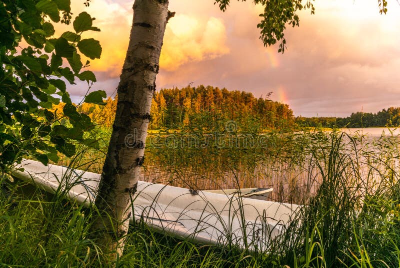 Ein hölzernes Ruderboot bei Sonnenuntergang auf den Ufern des ruhigen Saimaa Sees in Finnland unter einem nordischen Himmel mit e lizenzfreie stockfotos Ein hölzernes Ruderboot bei Sonnenuntergang auf den Ufern des ruhigen Saimaa Sees in Finnland unter einem nordischen Himmel mit e lizenzfreie stockfotos