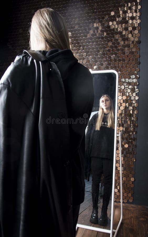 Ein jugendliches Mädchen mit langem blonden Haaren und leuchtendem Make-up sieht sich im Spiegel an. lizenzfreie stockfotografie