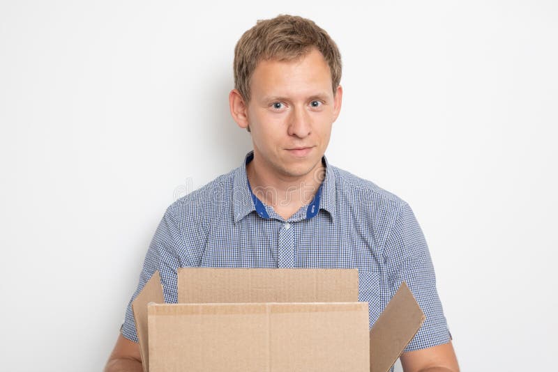Ein junger hübscher kaukasischer Mann, der eine offene Pappschachtel in seinen Händen und gelächelt hält stockfotografie Ein junger hübscher kaukasischer Mann, der eine offene Pappschachtel in seinen Händen und gelächelt hält stockfotografie