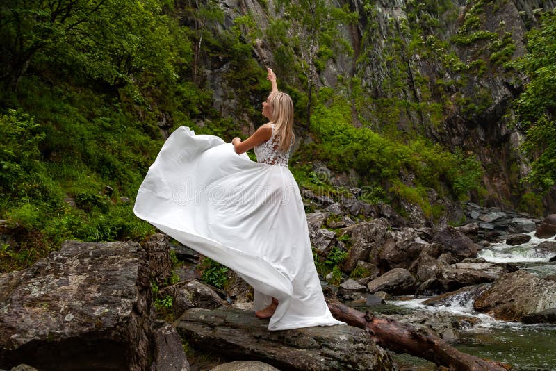 Ein junges blondes Mädchen in einer eleganten Haltung zieht ein Boudoir ankleiden oben in den Bergen gegen einen Wasserfall und S stockfoto Ein junges blondes Mädchen in einer eleganten Haltung zieht ein Boudoir ankleiden oben in den Bergen gegen einen Wasserfall und S stockfoto