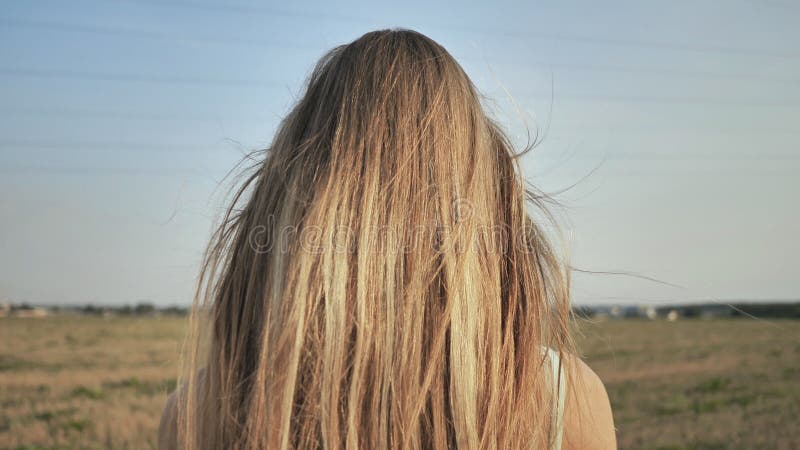 Ein junges blondes Mädchen steht mit ihr ihr langes Haar zurück demonstrierend