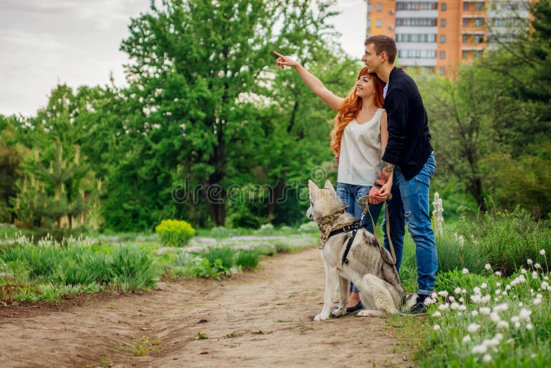 Ein junges gehendes Paar ein Hund im Park lizenzfreie stockfotos Ein junges gehendes Paar ein Hund im Park lizenzfreie stockfotos