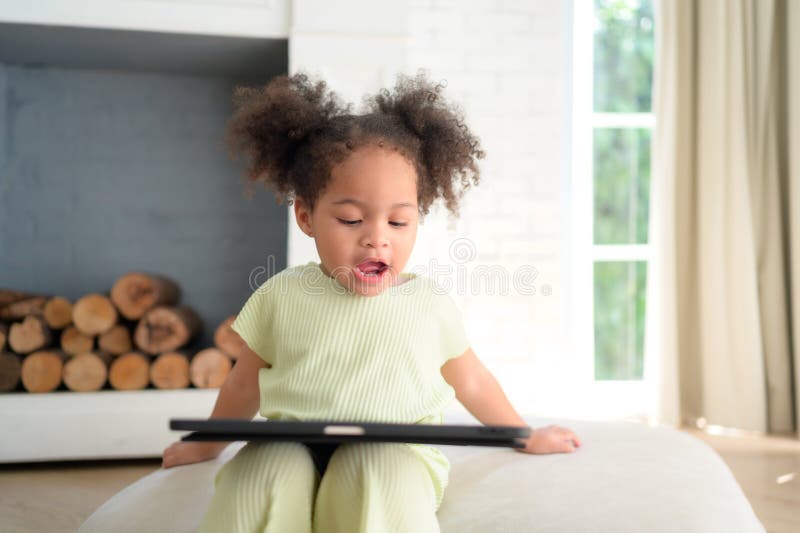 Ein junges, helles, süßes kleines Mädchen mit ihrer treuen Tablette, die sie glücklich macht stockbild
