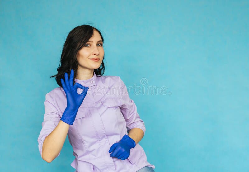 Ein junges Mädchen in den blauen medizinischen Handschuhen. die Krankenschwester oder die Doktorgesten mit dem okaysymbol. ein Mäd stockfotos