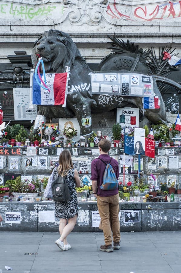 Ein junges Paar betrachtet die Ehrerbietungen, die beim Place de la Republique gelassen werden stockfotografie Ein junges Paar betrachtet die Ehrerbietungen, die beim Place de la Republique gelassen werden stockfotografie