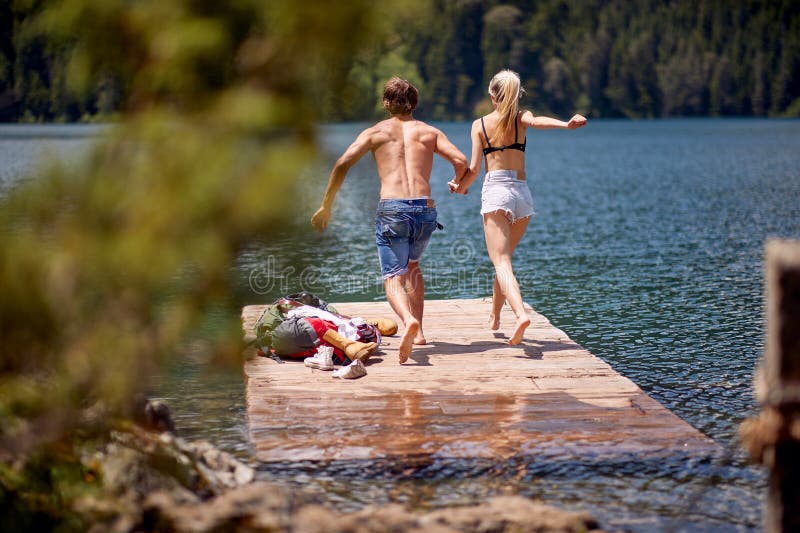 Ein junges Paar springt beim Bergwandern in den See. Wandern