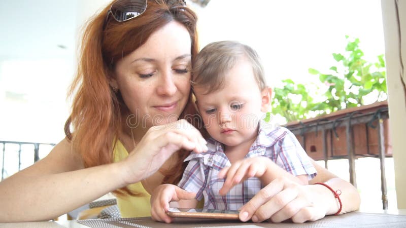 Ein kleiner Junge mit Mutter benutzt das Internet auf Smartphone stock video