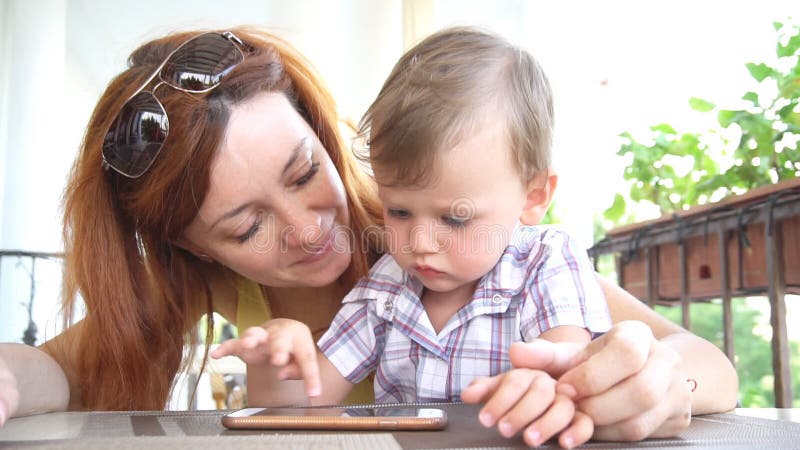 Ein kleiner Junge mit Mutter benutzt das Internet auf Smartphone stock video