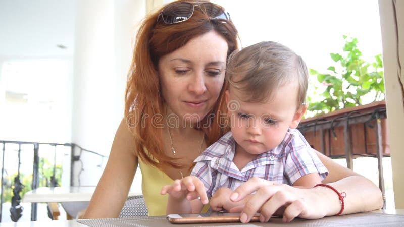 Ein kleiner Junge mit Mutter benutzt das Internet auf Smartphone stock footage