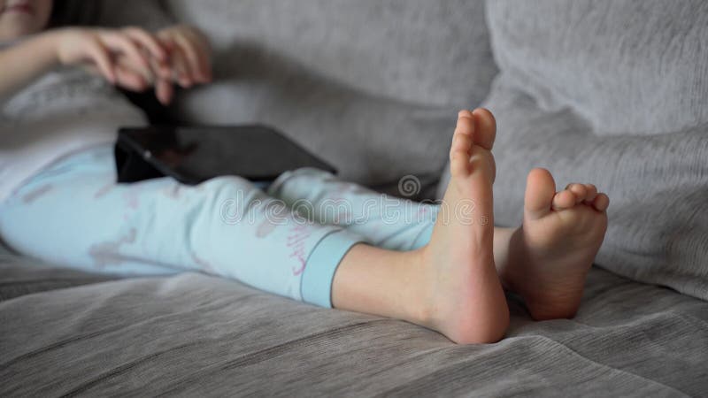 Ein Kleines Mädchen Liegt Zu Hause Auf Der Couch Und Schaut in Die Schwarze Tablette. Das Kind Spielt Und Sieht Das Video Stock Footage - Video von erholung, entspannen: 215211398