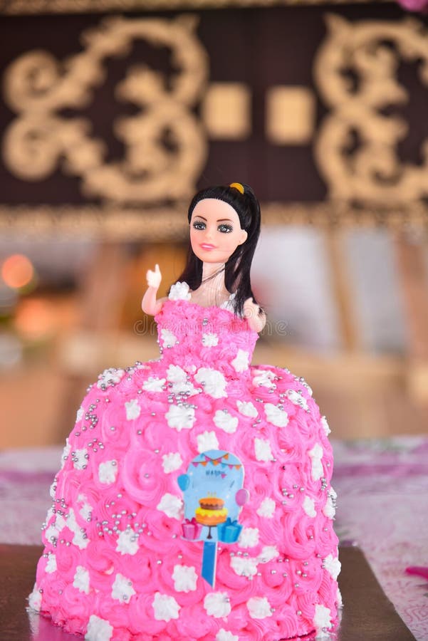 Ein köstlicher Puppenkuchen in lebhaftem Rosa mit zarten Silberkugeln und weißen Blumen verleiht dem Ganzen eine perfekte Note stockbild