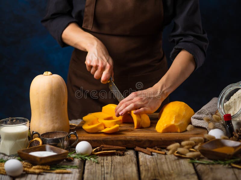 Ein Küchenchef schneidet einen Kürbis, um einen traditionellen, festlichen Kürbiskuchen zu backen. eine schöne Zusammensetzung der stockbild