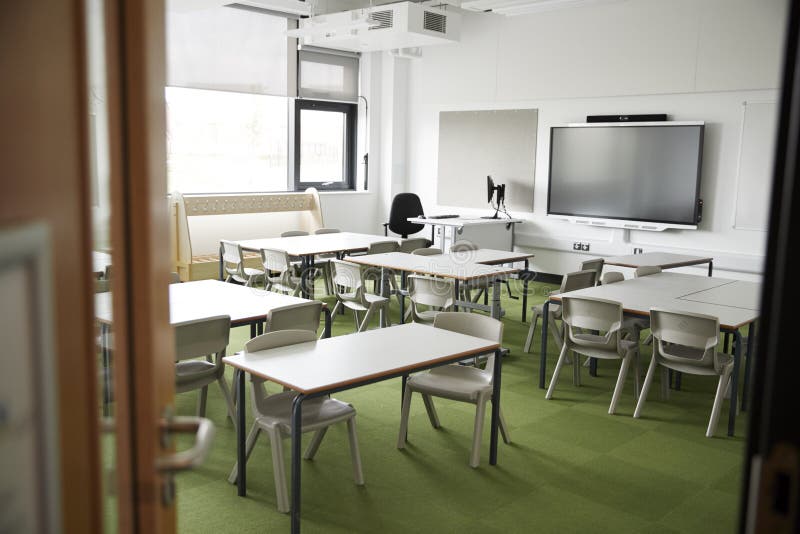 Ein leeres Klassenzimmer in einer Grundschule mit weißen Schreibtischen und den Stühlen, gesehen vom Eingang stockfoto Ein leeres Klassenzimmer in einer Grundschule mit weißen Schreibtischen und den Stühlen, gesehen vom Eingang stockfoto