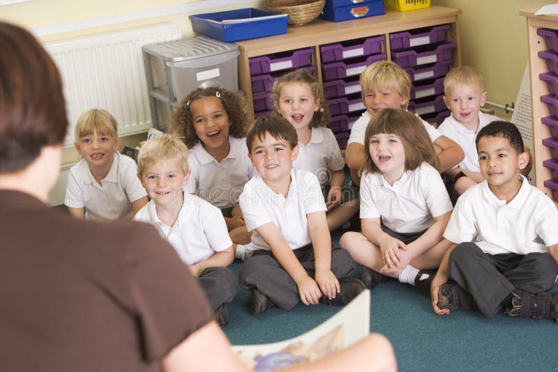 Ein Lehrer liest zu den Schulkindern in einer Kategorie lizenzfreie stockbilder Ein Lehrer liest zu den Schulkindern in einer Kategorie lizenzfreie stockbilder