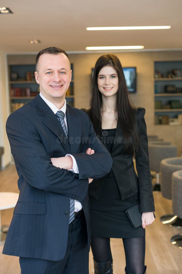 Ein lächelndes Mädchen mit einem Mann bei der Anzug-Stellung stockfotografie Ein lächelndes Mädchen mit einem Mann bei der Anzug-Stellung stockfotografie