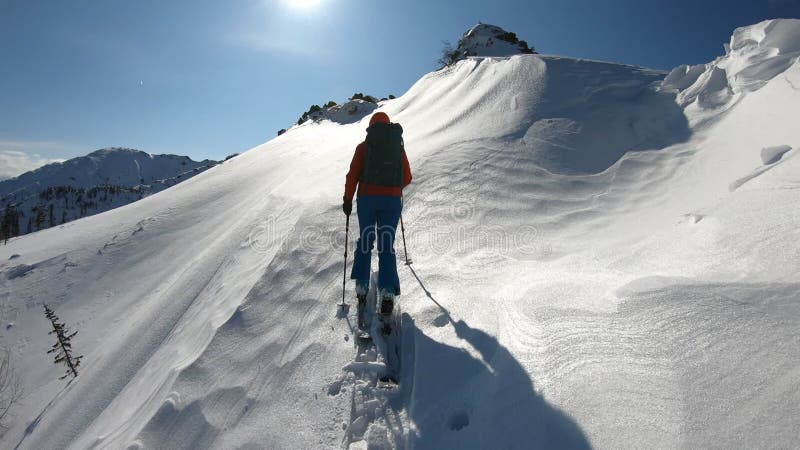 Ein Mann auf Skier in den Bergen in einem starken Schneesturm steigt nach oben. Abenteuerfreiheitsherausforderung. sonniger Tag in