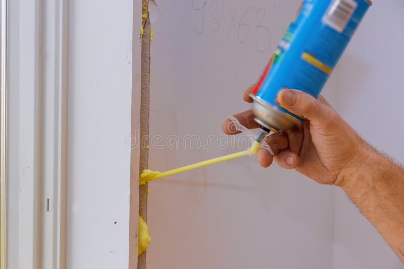 Ein Mann, der Polyurethanschaum verwendet, um ein Fenster auf einem gut aussehenden Arbeiter in Aktion zu installieren lizenzfreies stockbild Ein Mann, der Polyurethanschaum verwendet, um ein Fenster auf einem gut aussehenden Arbeiter in Aktion zu installieren lizenzfreies stockbild