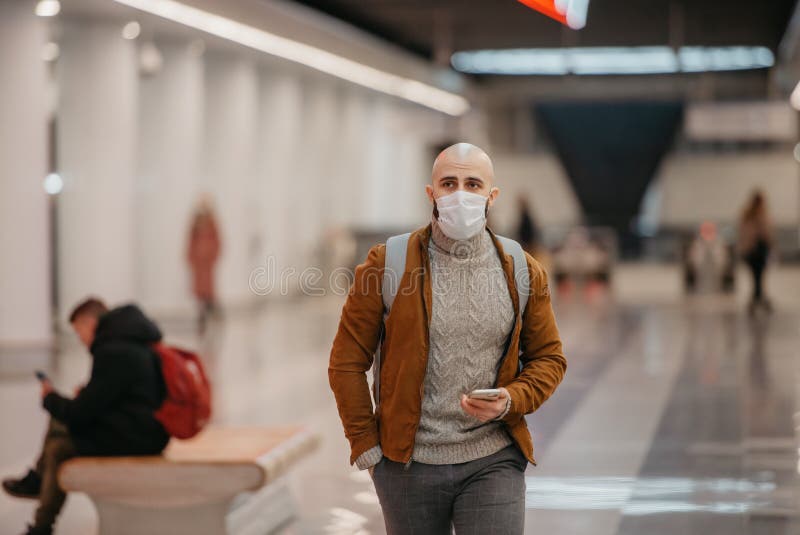 Ein Mann in einer Gesichtsmaske benutzt ein Smartphone, während er auf einen U-Bahn-Zug wartet stockfoto