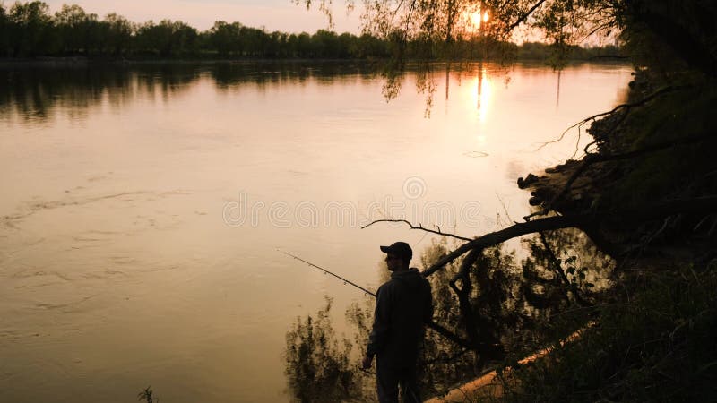 Ein Mann fischt an den Ufern eines großen Flusses.