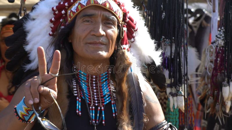 Ein Mann gekleidet als gebürtige Indianer nahe bei seinem Shopandenken Langsame Bewegung