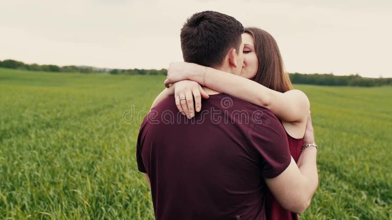 Ein Mann und eine Frau schließen sich Händen an und gehen auf einem Gebiet, dem Umarmen und dem Küssen Langsames MO, Steadicam-Sc