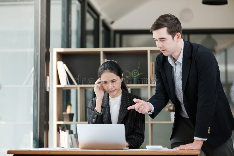 Ein Mann und eine Frau sitzen an einem Schreibtisch mit einem Laptop stockfotografie