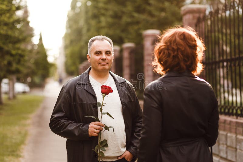 Ein Mann von mittlerem Alter gibt einer Frau, romantisches Datum eine Rose