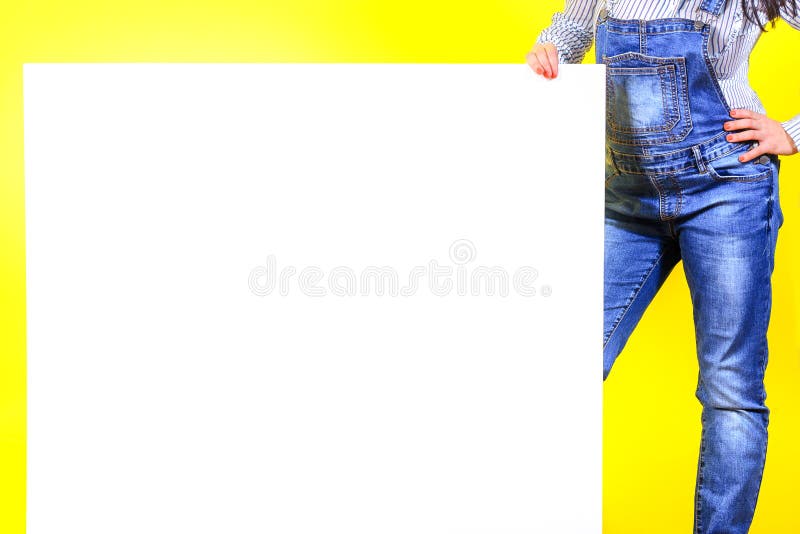 Ein Mädchen in einem Smoking auf einem gelben Studiohintergrund hält ein großes weißes Blatt lizenzfreie stockfotos Ein Mädchen in einem Smoking auf einem gelben Studiohintergrund hält ein großes weißes Blatt lizenzfreie stockfotos