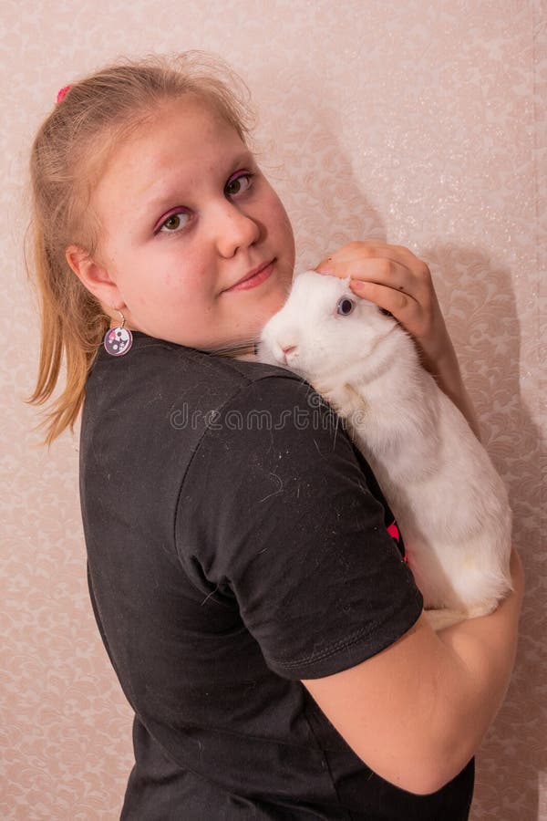 Ein Mädchen hält ein schönes weißes Kaninchen in den Armen. stockfotografie