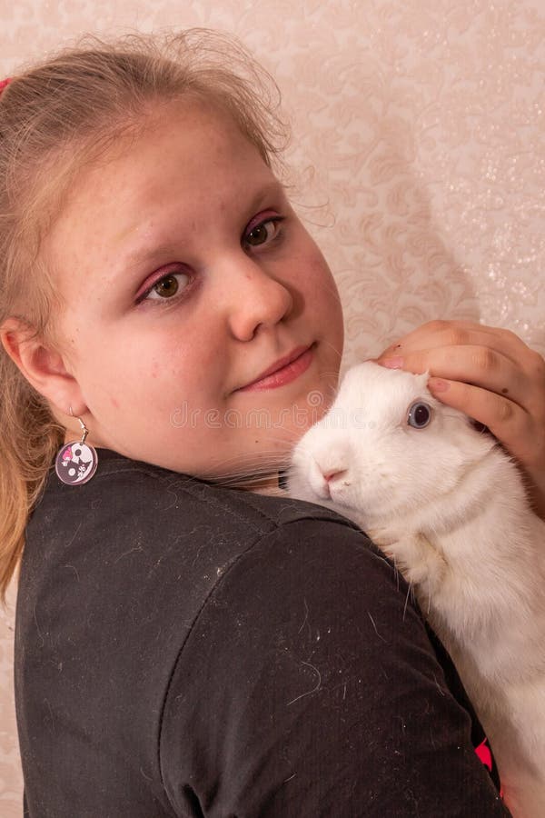 Ein Mädchen hält ein schönes weißes Kaninchen in den Armen. lizenzfreies stockfoto