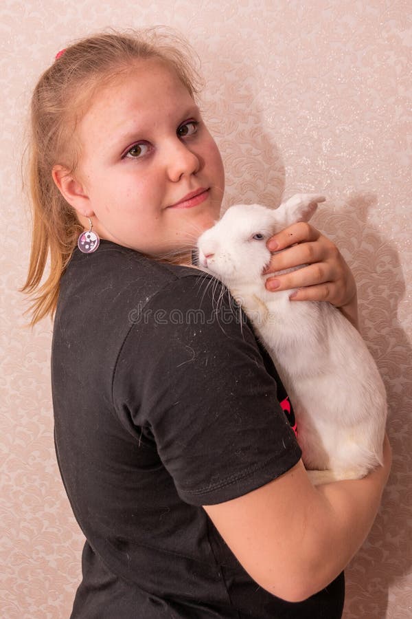 Ein Mädchen hält ein schönes weißes Kaninchen in den Armen. stockfotografie
